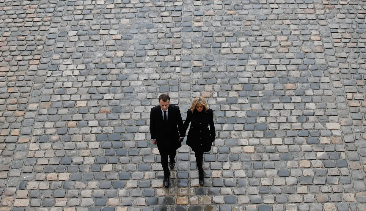 Presiden Prancis Emmanuel Macron bersama istrinya Brigitte meninggalkan lokasi seusai upacara pemakaman dan penghormatan terhadap Letnan Kolonel Polisi Arnaud Beltrame di Hotel des Invalides, Paris, Rabu (28/3). (AP/Christophe Ena)