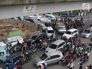 Petugas Dishub mengatur arus lalu lintas di Simpang Matraman, Jakarta, Rabu (19/7). Rekayasa lalu lintas terkait pembangunan simpang tidak sebidang atau underpass di kawasan tersebut akan diuji coba pada 20-27 Juli. (Liputan6.com/Immanuel Antonius)