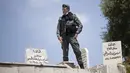 Seorang petugas polisi perbatasan Israel berdiri di tepi kuburan saat dia menyaksikan jemaah tiba untuk sholat Jumat pertama selama bulan suci Ramadhan di Masjid Kubah Batu di Kota Tua Yerusalem, Jumat (16/4/2021).  (AP Photo/Maya Alleruzzo)