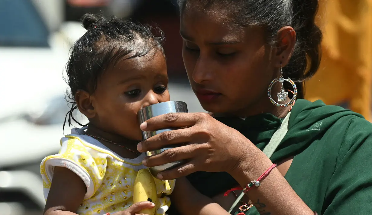 Seorang ibu membantu putrinya untuk minum air pada suatu hari di musim panas di Amritsar pada tanggal 25 April 2024. (Narinder NANU/AFP)