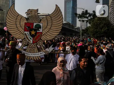 Warga membawa lambang Garuda Pancasila saat Kirab Pancasila pada Hari Bebas Kendaraan Bermotor (HBKB) di kawasan Bundaran HI, Jakarta, Minggu (28/5/2023). (Liputan6.com/Johan Tallo)