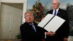 Presiden AS Donald Trump didampingi wakilnya Mike Pence, menunjukkan dokumen pengumuman Yerusalem yang akan ditandatangani di Ruang Penerimaan Diplomatik Gedung Putih, Washington, Rabu (6/12). (AP Photo / Evan Vucci)