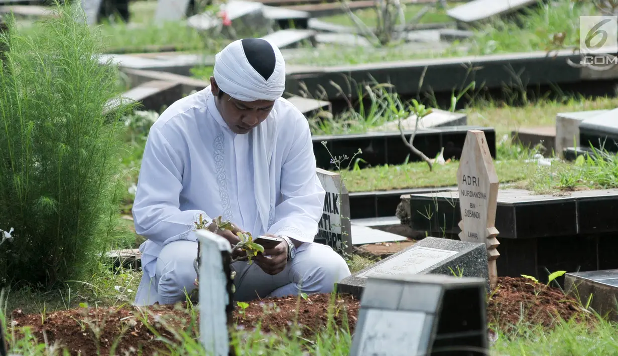 Umat Muslim membaca doa di depan pusara makam di Tempat Pemakaman Umum (TPU) Karet Bivak, Jakarta, Minggu (25/6). Hari pertama Lebaran, sejumlah warga memadati TPU untuk melangsungkan tradisi ziarah usai salat Idul Fitri. (Liputan6.com/Yoppy Renato)