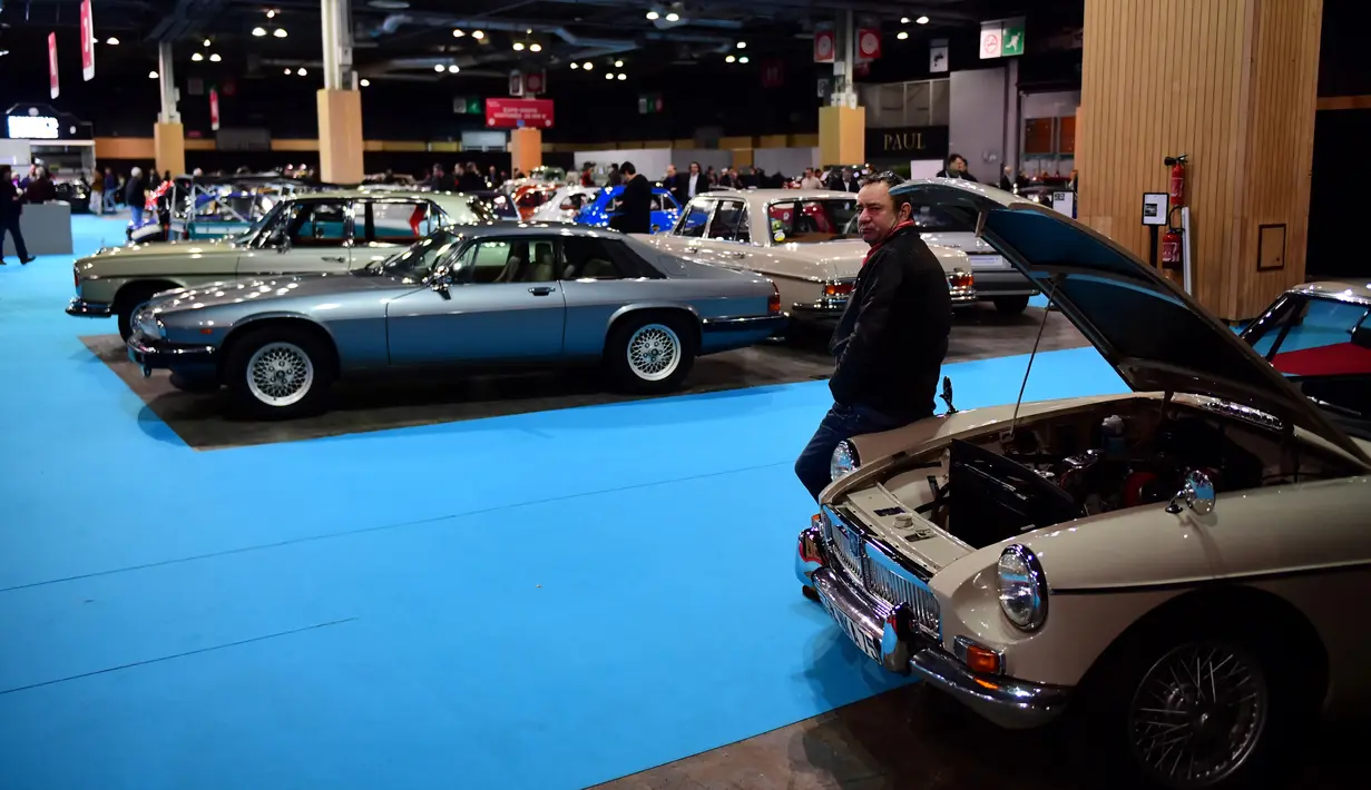 Seorang pria berdiri disamping sebuah mobil tua yang ditampilkan selama pameran mobil klasik Retromobile di Porte de Versailles, di Paris (4/2/2020). Retromobile berlangsung dari 5 Februari hingga 9 Februari 2020. (AFP Photo/Martin Bureau)