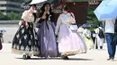 Para wisatawan yang mengenakan pakaian tradisional Hanbok menggunakan payung untuk melindungi diri dari terik matahari di Istana Gyeongbokgung di Seoul,  Korea Selatan, Senin,  3 Agustus 2026. (AFP/  Jung Yeon-je)