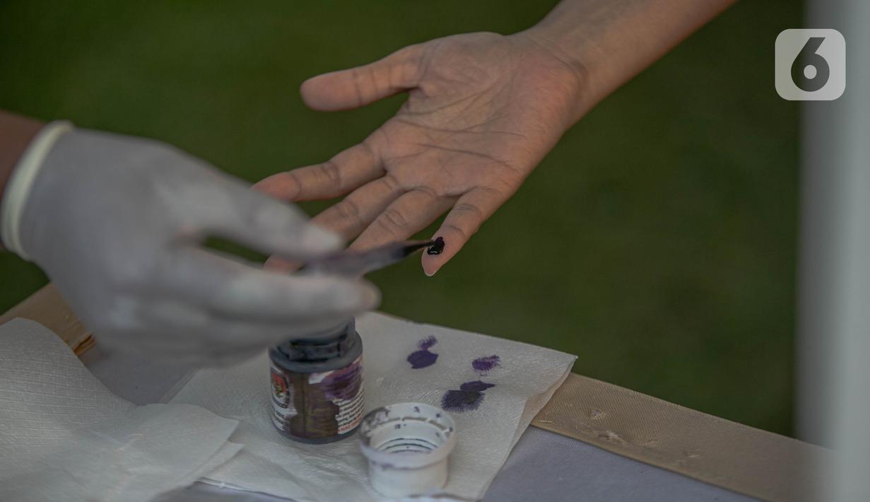 Petugas menandai jari warga dengan tinta usai mencoblos di Tempat Pemungutan Suara (TPS) 69 Pisangan, Ciputat, Tangerang Selatan, Rabu (9/12/2020). Protokol kesehatan dipraktikkan cukup ketat di TPS di Pilkada Tangerang Selatan untuk menghindari penularan COVID-19. (Liputan6.com/Faizal Fanani)