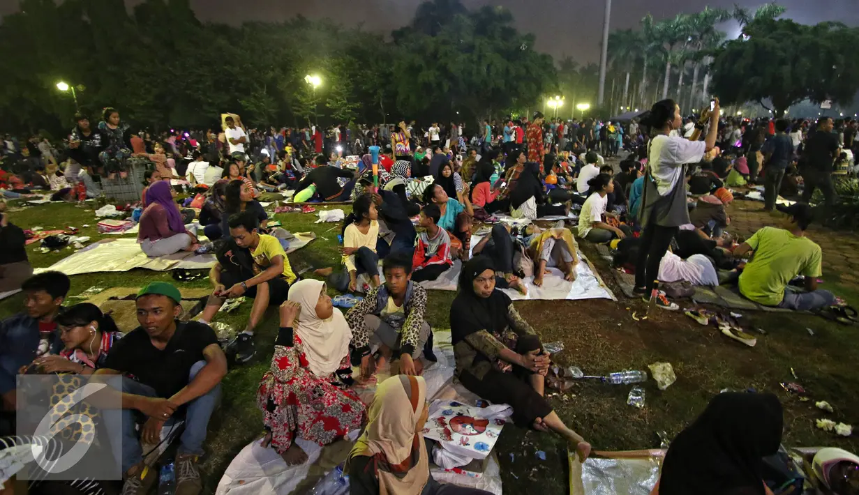 Warga saat menyaksikan pesta kembang api di kawasan Monas, Jakarta, Jumat (1/1). Antusiasme warga yang memadati Monas saat malam pergantian tahun membuat langit di kawasan tersebut dimeriahkan dengan pesta kembang api. (Liputan6.com/Immanuel Antonius)