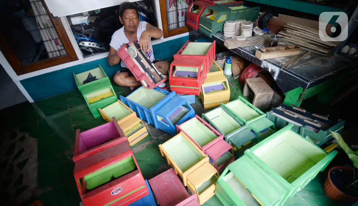 Perajin Uus Saputra (58) menyelesaikan mobil mainan dari limbah kayu bekas di Kelurahan Ciputat, Tangerang Selatan, Banten, Rabu (28/10/2020). Mobil mainan yang menggunakan bahan baku kayu tersebut dijual seharga Rp 50 ribu hingga Rp 250 ribu tergantung ukuran. (merdeka.com/Dwi Narwoko)