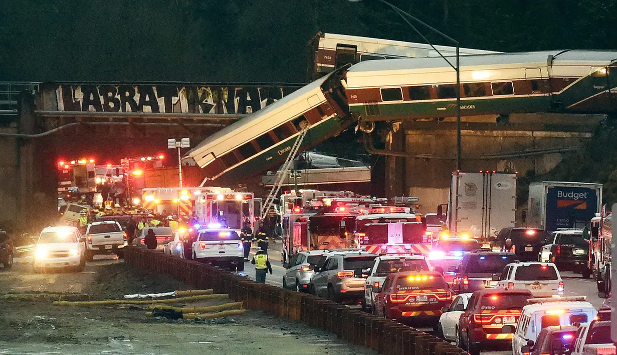 Kereta Amtrak yang terjatuh dari jembatan dan menimpa kendaraan-kendaraan terlihat di jalan raya di Interstate di DuPont, Washington, AS (18/12). Dilaporkan beberapa orang tewas dalam insiden ini. (Steve Bloom /The Olympian via AP)