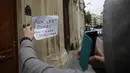 Seorang wanita berdiri sambil memegang kertas di depan kantor Google di Paris, Selasa (24/5). Pejabat keuangan Prancis melakukan penggerebekan kantor raksasa internet Google sebagai bagian dari penyelidikan penggelapan pajak. (MATTHIEU ALEXANDRE/AFP)