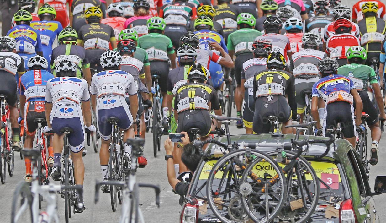 Seorang ofisial tim tengah memotret pebalap saat melewati daerah Indarung pada Etape 6 dari Padang Pariaman menuju Sawahlunto, Sumatera Barat, Kamis (11/8/2016). (Bola.com/Nicklas Hanoatubun)