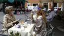 Seorang wanita yang mengenakan pelindung wajah minum kopi di sebuah kafe di Roma, Italia, Senin (18/5/2020). Italia secara perlahan melonggarkan kebijakan lockdown akibat pandemi virus corona COVID-19. (Cecilia Fabiano/LaPresse via AP)