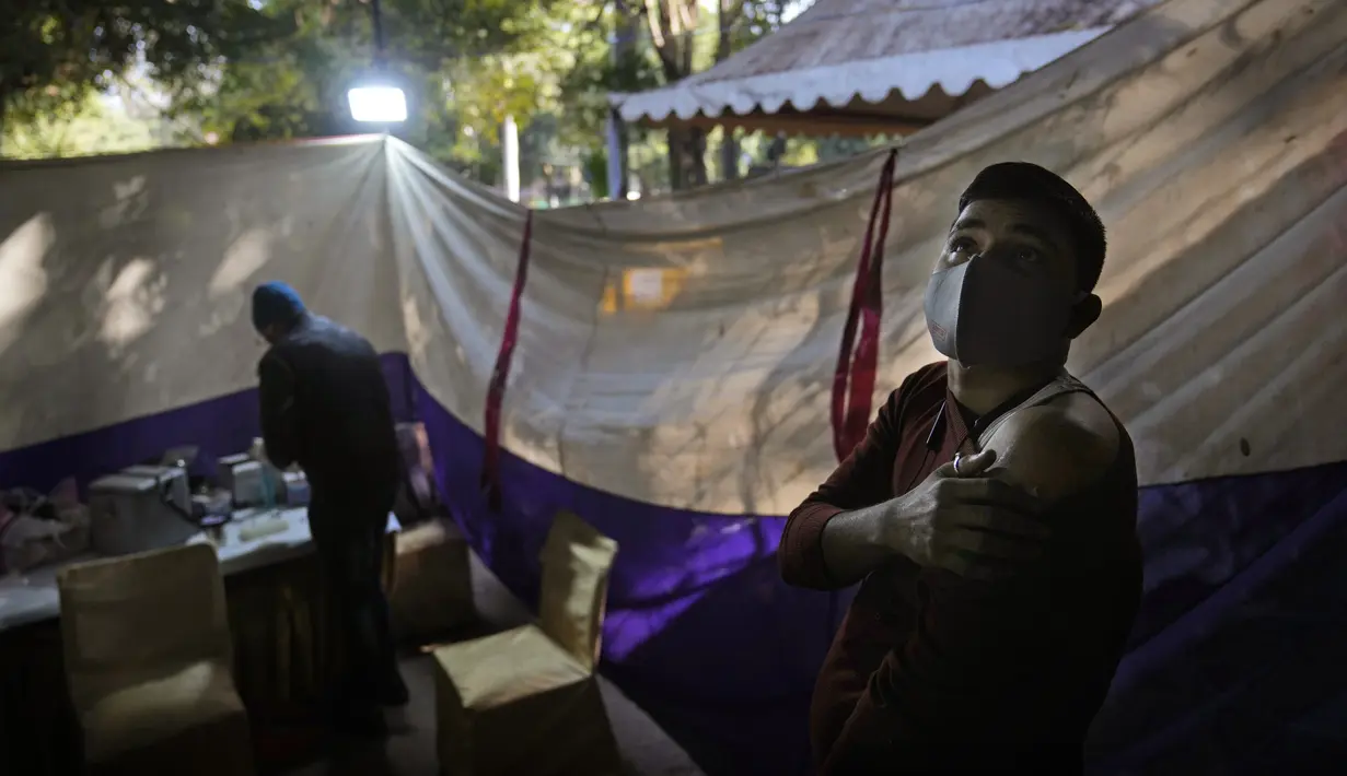 Reaksi seseorang ketika menunggu setelah menerima vaksin COVID-19 di sebuah pasar di New Delhi, Rabu (29/12/2021). Di India, yang telah kembali normal setelah dihantam tsunami COVID-19 tahun ini, omicron sekali lagi menimbulkan ketakutan, dengan lebih dari 700 kasus dilaporkan. (AP Photo/Manish Sw