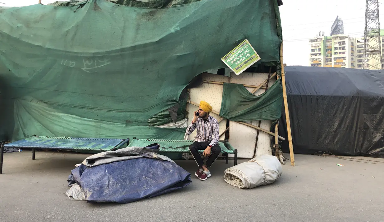 Seorang petani Sikh berbicara di telepon genggam saat para petani membongkar bangunan sementara yang digunakan untuk protes selama setahun mereka di Ghazipur, pinggiran New Delhi, India, Kamis (9/12/2021). (AP Photo/Altaf Qadri)
