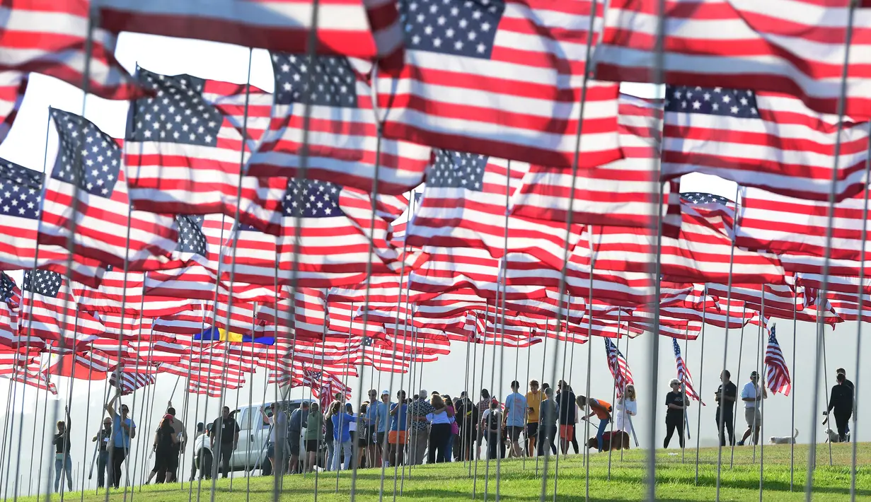 Orang-orang membantu pengibaran bendera AS untuk peringatan 20 tahun serangan 9/11 di Pepperdine University di Malibu, California, Rabu (8/9/2021). Selama 14 tahun, universitas itu memperingati tragedi 11 September 2001 dengan mengibarkan sekitar 3.000 bendera Amerika. (Frederic J. BROWN/AFP)