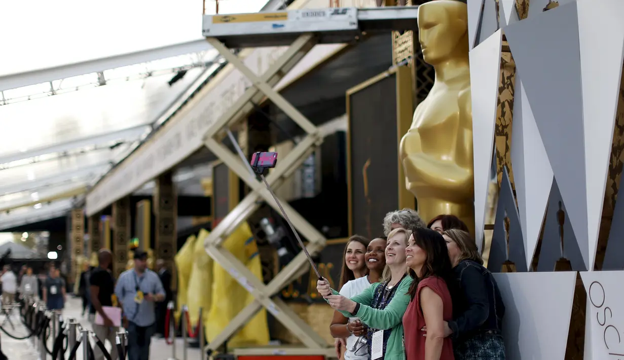 Sejumlah wanita berselfie dengan latar belakang patung Oscar 2016 di luar Teater Dolby, Hollywood, California, Jumat (26/2). Acara penghargaan Academy Awards ke-88 ini akan berlangsung pada Minggu (28/2) waktu setempat. (REUTERS/ Mario Anzuoni)
