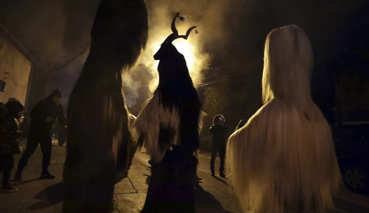 Penari bertopeng melakukan ritual kuno mengusir roh jahat di jalan-jalan Batanovci, Bulgaria, Kamis malam (13/1/2022). Untuk dua tahun ini festival topeng memiliki arti ekstra: orang-orang berharap itu akan membawa kelegaan dari kesengsaraan pandemi corona. (AP/Valentina Petrova)