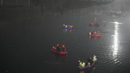 Tim penyelamat di kapal mencari di sungai Machchu di sebelah jembatan kabel yang runtuh di kota Morbi di negara bagian barat Gujarat, India, Senin, 31 Oktober 2022. Sedikitnya 81 orang tewas akibat kejadian tersebut. (AP/Ajit Solanki)