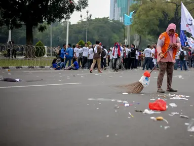 Petugas kebersihan membersihkan sampah saat peringatan hari buruh sedunia yang jatuh pada tanggal 1 Mei di depan Istana Merdeka, Jakarta, Jumat (1/5/2015). Aksi demo May Day menyisahkan sejumlah sampah berserakan di jalan. (Liputan6.com/Faizal Fanani)