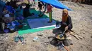 Seorang warga memasak di dekat tenda di sebuah lapangan terbuka di Marapokot, Nagekeo, Nusa Tenggara Timur, Senin, 17 Agustus 2026, (AFP/ Juni Kriswanto)
