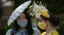 Anna Gilder (kanan) bersama Yuan Li berpose untuk fotografer mengenakan topi hiasan mereka pada hari pertama pacuan kuda Royal Ascot di Ascot, Inggris, Selasa (15/6/2021). Balap kuda eksklusif yang hanya dihadiri kalangan elit Inggris itu menjadi tradisi tahunan sejak 1711. (AP Photo/Alastair Grant)