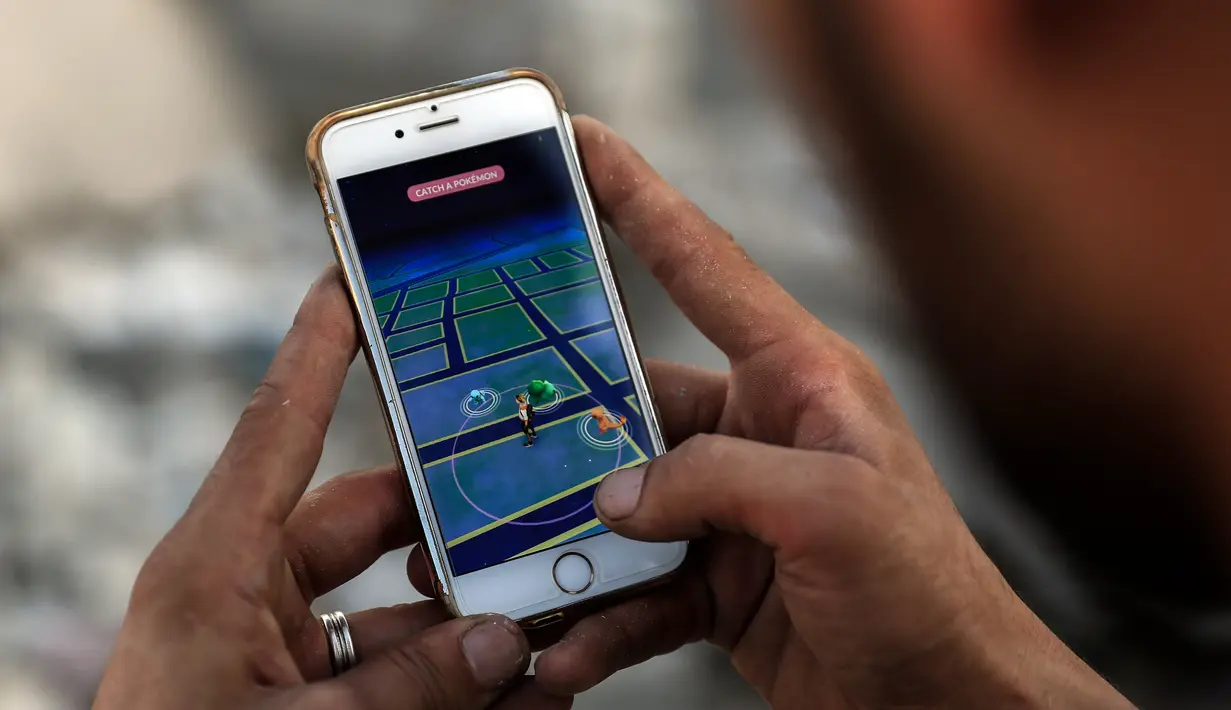 Seorang pria bermain Pokemon Go di daerah konflik Suriah, Damaskus (23/7). Ia tampak menemukan Pokemon diantara reruntuhan. (AFP PHOTO / Sameer Al-Doumy)