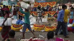 Pembeli berjalan melewati pedagang yang menjual bunga di pasar grosir di Bengaluru, India, Rabu (13/4/2022). Orang-orang telah kembali beraktivitas normal setelah pihak berwenang mencabut pembatasan COVID-19 termasuk mengenakan masker wajah di tempat-tempat umum. (AP Photo/Aijaz Rahi)