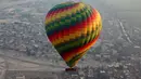 Balon udara panas terbang membawa wisatawan mengudara di atas kota Luxor, Kairo, Mesir (13/12). Wisatawan akan menikmati pemandangan situs-situs kuno di kota Luxor dari atas balon udara panas.  (Reuters/Amr Abdallah Dalsh)