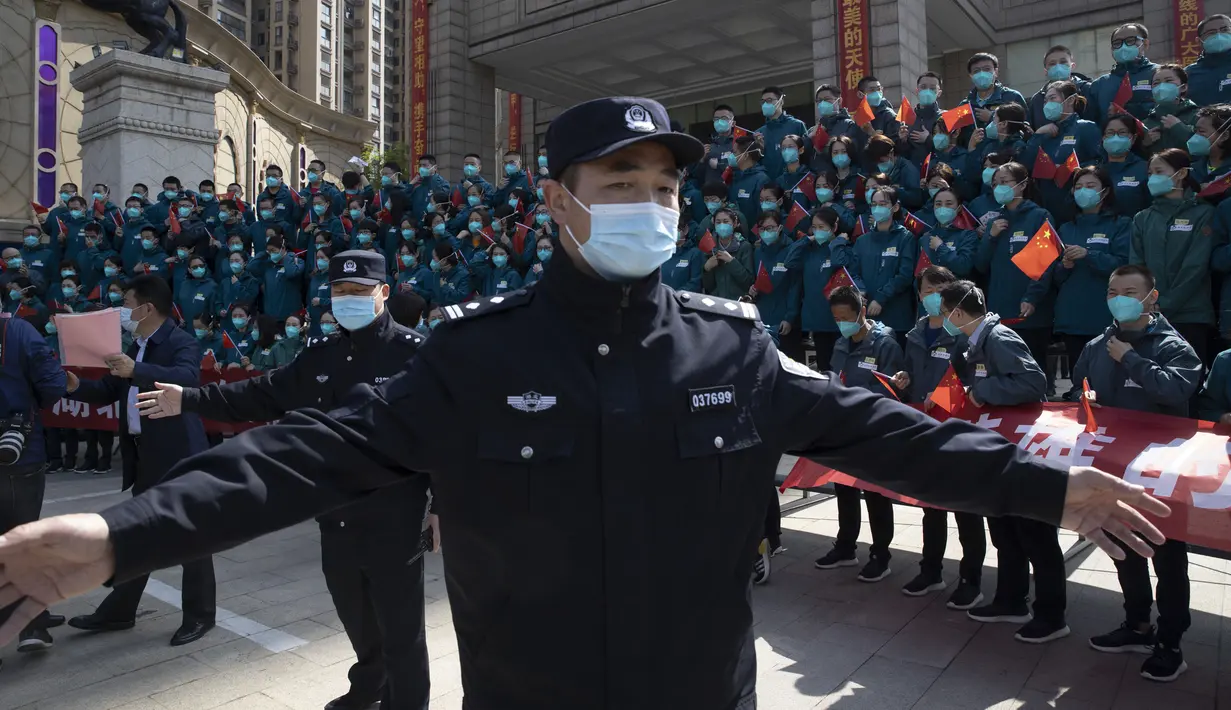 Polisi berjaga saat upacara perpisahan untuk kelompok petugas medis terakhir yang datang dari luar Wuhan dalam membantu kota selama wabah virus corona COVID-19 di Wuhan, Provinsi Hubei, China, Rabu (15/4/2020). Wuhan mulai pulih setelah lebih dari dua bulan melawan COVID-19. (AP Photo/Ng Han Guan)