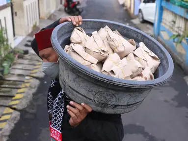 Warga membawa nasi bungkus untuk warga yang terdampak Covid-19 di di RW 03, Kelurahan Gandasari, Kecamatan Jatiuwung, Kota Tangerang, Jumat (11/6/2021).  Dampak penerepan lockdown membuat warga sekitar yang sehat melakukan aksi bersama untuk menyuplai makanan.  (Liputan6.com/Angga Yuniar)