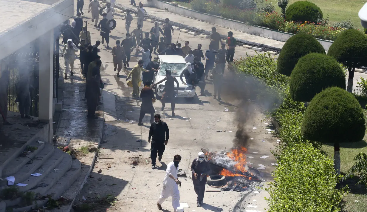 Pendukung mantan Perdana Menteri Pakistan Imran Khan merusak sebuah mobil di dalam kompleks Radio Pakistan saat memprotes penangkapan pemimpin mereka, di Peshawar, Pakistan, Rabu, 10 Mei 2023. (AP Photo/Muhammad Sajjad)
