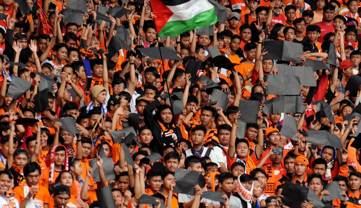 Salah satu Jakmania mengibarkan bendera Palestina saat menyaksikan laga Persija Jakarta kontra Persib Bandung, di Stadion GBK, (10/8/2014). (Liputan6.com/Helmi Fithriansyah)