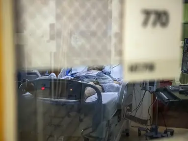 Seorang pasien terinfeksi Covid-19 duduk di tempat tidur di ruang tekanan negatif di bangsal ICU UMass Memorial Medical Center di Worcester, Massachusetts, Selasa (4/1/2022). Rumah sakit mengklaim mereka dipenuhi pasien dan tidak memiliki banyak tempat tidur tersisa jika ada. (Joseph Prezioso/AFP)