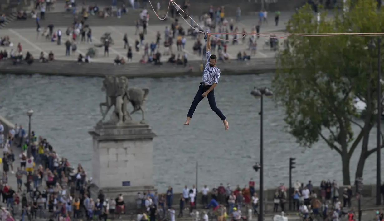 Akrobatik Nathan Paulin tampil untuk kedua kalinya meniti seutas tali slackline pada ketinggian 70 meter antara Menara Eiffel dan Theater Chaillot di Paris, Minggu (19/9/2021). Pada 2019, pria Prancis itu melakukan slackline walk setinggi 150 meter dengan panjang 510 meter. (AP Photo/Francois Mori)