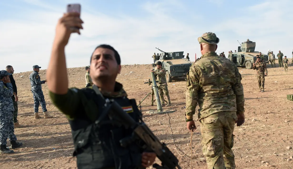 Seorang anggota pasukan Irak berselfie sebelum menembakkan mortir ke arah militan ISIS di Qayyarah, selatan Mosul, (21/10). (AFP PHOTO/Bulent KILIC)