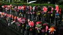 Patung-patung Jizo terlihat saat seorang pria dengan mengenakan payung melintas di Kuil Zojoji, Tokyo pada 22 Juni 2020. Jizo adalah pelindung dari anak-anak yang belum sempat lahir atau meninggal dalam kandungan dan saat masih bayi. (Photo by Philip FONG / AFP)