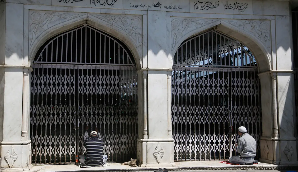 Muslim Kashmir berdoa di luar gerbang tertutup sebuah kuil muslim selama bulan puasa Ramadan di Srinagar, Kashmir yang dikuasai India (8/5/2020). (AP Photo/Mukhtar Khan)