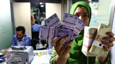 Seorang karyawan menunjukkan uang pecahan rupiah yang telah ditukar di mobil kas Bank Indonesia (BI) di Lantai 7 SCTV Tower, Jakarta, Jumat (24/6). BI membawa uang Rp 700 juta untuk ditukarkan oleh para karyawan EMTEK Group. (Liputan6.com/Fery Pradolo)