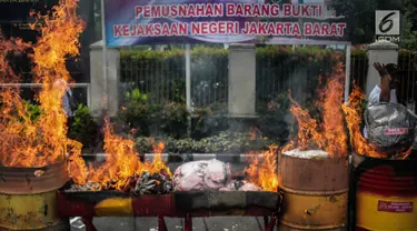 Petugas membakar barang bukti tindak pidana umum di lapangan Kejaksaan Negeri Jakarta Barat, Selasa (11/12). Barang bukti yang dimusnahkan berupa senjata Api, psikotropika, makanan, obat-obatan dan kosmetika. (Liputan6.com/Faizal Fanani)