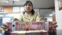 Teller menunjukkan mata uang rupiah di penukaran uang di Jakarta, Rabu (10/7/2019). Nilai tukar rupiah terhadap dolar Amerika Serikat (AS) ditutup stagnan di perdagangan pasar spot hari ini di angka Rp 14.125. (Liputan6.com/Angga Yuniar)