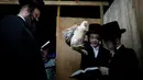 Dua remaja Yahudi Ultra-Ortodoks membaca doa saat ia melakukan ritual Kaparot, di Ashdod, Israel, (9/10). Ritual ini dilakukan menjelang Hari Penebusan Yahudi, Yom Kippur. (REUTERS/Amir Cohen)