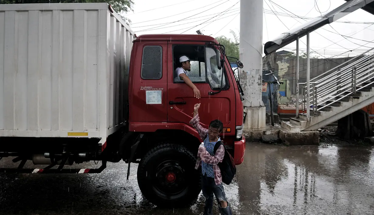 Seorang anak menerima upah dari jasa membersihkan kaca mobil di Jalan Raya Bekasi, Cakung, Jakarta, Selasa (17/3/2020). Dengan sabun yang dikemas dalam botol, anak-anak ini mendapatkan uang seikhlasnya dari pengendara walaupun dapat mengancam keselamatan mereka. (merdeka.com/Iqbal S Nugroho)