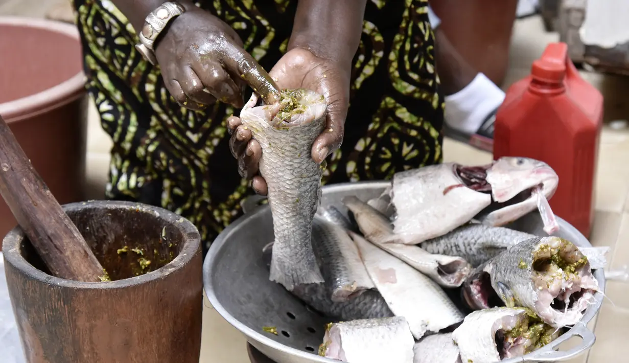Koki Senegal Thiane Ngom menyiapkan "thiebou dieune" tradisional di rumahnya di Dakar pada 15 Desember 2021. Thiebou dieune yang berarti nasi dengan ikan dalam bahasa Wolof ini butuh waktu tiga jam untuk dimasak. Hidangan khas Senegal ini biasanya disajikan saat makan siang. (SEYLLOU/AFP)