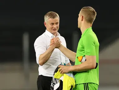 Pelatih Manchester United, Ole Gunnar Solskjaer bersalaman dengan kiper Copenhagen, Karl-Johan Johnsson usai pertandingan perempat final Liga Europa di RheinEnergieStadion, di Cologne, Jerman (10/8/2020). MU lolos ke babak semifinal Liga Europa usai menang 1-0. (AFP/Pool/Wolfgang Rattay)