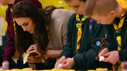 Kate Middleton membuat kue Pramuka bersama sejumlah anak-anak dalam acara Cub Scout Pack di Kings Lynn, Inggris (14/12). Dalam acara ini Kate Middleton bertemu dan bermain dengan 24 anak-anak yang ikut berpartisipasi. (Reuters/Ben Stansall/Pool)