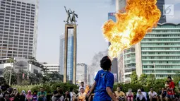 Seorang pria melakukan atraksi menyembur api di area Car Free Day kawasan MH Thamrin, Jakarta, Minggu (4/6). Pria yang tergabung dalam kelompok seniman Kuda Lumping tersebut melakukan aksi berbahaya untuk mencari nafkah. (Liputan6.com/Faizal Fanani)