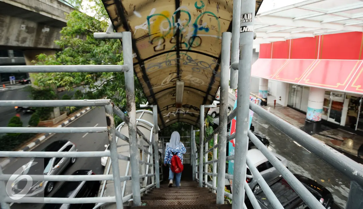 Warga menuruni tangga Jembatan Penyeberangan Orang (JPO) di Jalan Iskandarsyah, Jakarta, Selasa (1/11). Tampak kondisi atap JPO yang kotor dipenuhi coretan. (Liputan6.com/Helmi Fithriansyah)