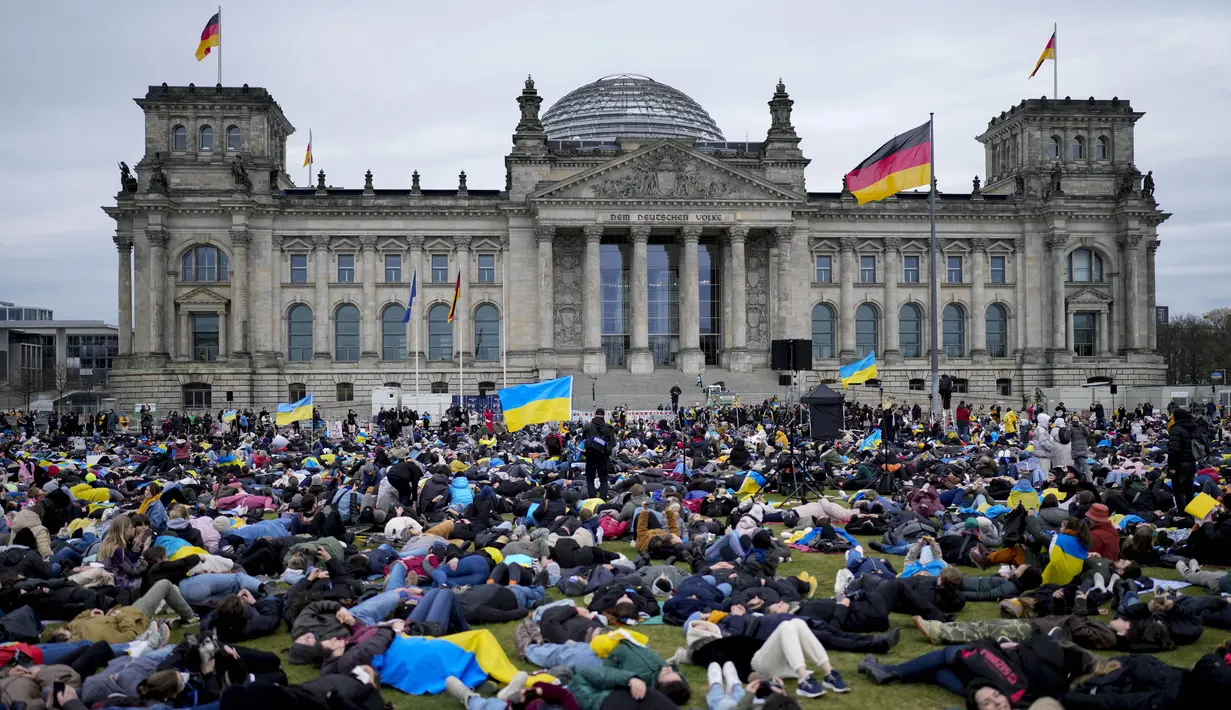 Orang-orang berbaring di tanah melambangkan mereka yang tewas dalam perang di Ukraina selama demonstrasi menentang invasi Rusia, di depan gedung Reichstag di Berlin, Jerman, 6 April 2022. Pengunjuk rasa menuntut Berlin berhenti membeli minyak dan gas Rusia. (AP Photo/Markus Schreiber)