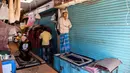 Umat Muslim melaksanakan salat di depan toko-toko yang tutup di sebuah pasar selama bulan Ramadan saat penerapan lockdown di New Delhi, Senin (4/5/2020). Di emperan toko-toko yang tutup, umat muslim salat berjemaah dengan menjaga jarak dan lainnya membaca kitab suci Alquran. (Sajjad HUSSAIN/AFP)