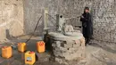 Perempuan Afghanistan, Sitara Wafadar yang menyamar sebagai laki-laki mengambil air di rumahnya, Provinsi Nangarhar, 20 Maret 2018. Setiap pagi, Sitara memakai kemeja, celana panjang dan sandal yang biasa dikenakan pria Afganistan (NOORULLAH SHIRZADA/AFP)